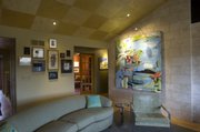 Subflooring squares on the ceiling help set off a giant abstract piece from Collins and other artists’ work on an opposite wall. The 1950s-style furnishings help balance the old with the new.