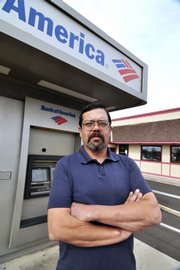 Recently unemployed engineer Arthur Santa-Maria stands in front of a Bank of America ATM in Los Lunas, N.M. Santa-Maria was surprised to learn he must pay fees to withdraw his unemployment money using a state-issued bank debit card.