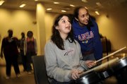 Big Sister Erin Resa, a Kansas University sophomore from Lenexa, looks on as her Little Sister Emaleigh Clark, a sixth-grader at Wakarusa Valley School, takes the drum part during a performance on the game “Rock Band” at the Lawrence Public Library, 707 Vt. Resa, who was matched to Clark through Big Brothers Big Sisters of Douglas County, has been a mentor to Clark for a little more than a year. The two girls usually hang out once a week.