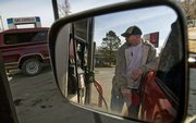 Jason Smith fills up his car with gasoline at Woody’s Gas Express in North Lawrence. Gasoline prices are expected to climb this summer but not to last year’s record highs.