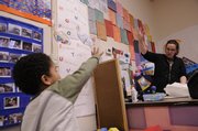 Sylas Canada, 4, reaches to do a distant high-five with his teacher, Katie Urban, at the Ballard Community Center.