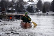 Lowell Bottrell paddles through the current in his neighborhood as the Red River continues to rise, Friday in Briarwood, N.D. Bottrell is one of the few left in his neighborhood.