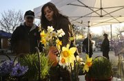 Kym Scafe, Lawrence, a worker with Pendleton's Country Market, retrieves a vase of daffodils for Lawrence resident Michael Rapport on the first day of the Farmer's Market Saturday, April 11, 2009.