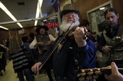 Late income tax filers make their way through the glass doors as members of the Alferd Packer Memorial String Band including Steve Mason, Lawrence, front, Jim Brothers, Lawrence, left, and Steve Goeke, Holt, Mo., perform the William Tell Overture during the final push before closing on Tax Night 2009 at the downtown Lawrence post office.