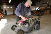 Paul Baumchen, Lawrence Parks and Recreation horticulturist, checks over a city lawn mower last week before heading out to mow in several city parks.