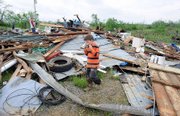 Nathan Renner, 9, plays a harmonica Saturday near the wreckage of a destroyed trailer owned by Kenny Walton in Nina Ridge, Ky. Gov. Steve Beshear declared a state emergency in central and south eastern Kentucky on Saturday after strong storms barreled through the Midwest, killing 6.