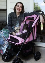 Melissa Garcia and her two dogs, Daisy Mae, left, and Isabella, show off Garcia’s stroller and dog outfits obtained for great deals Monday at her home in Edmond, Okla. Garcia pens consumerqueen. com, a blog read by at least 30,000 people each month and by corporate America.