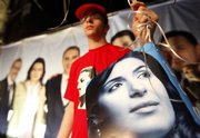 A man carries a picture of Lebanese election candidate Nayla Tueni, who is seeking to claim her slain father’s seat, An-Nahar newspaper general manager and legislator Gibran Tueni, in Beirut, Lebanon.