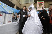 An Iranian groom talks with his bride as they arrive Friday at a polling station to vote for the presidential elections in downtown Tehran, Iran. Iranians packed polling stations from boutique-lined streets in north Tehran to conservative bastions in the countryside Friday.