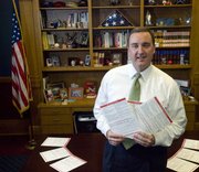 In this Feb. 14, 2008 file photo, Secretary of State Ron Thornburgh holds copies of voter registration applications in Topeka, Kan. Thornburgh ended his bid to be the next Kansas governor Monday, saying he lacked the funding and support to challenge for the Republican nomination.