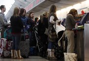 In this Dec. 21, 2008, file photo, travelers queue up at a ticketing counter at Denver International Airport. United Airlines has recently started charging passengers an extra $5 if you pay a $15 baggage charge at the airport instead of online.