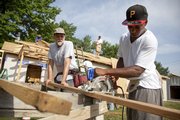 Kansas University junior running back Daniel Porter keeps an eye on the power saw as he and Lawrence volunteer Steve Hillmer cut a board for the roof of a Habitat for Humanity home on the west corner of 15th and Elmwood Saturday, July 11, 2009. The home will be given to the Mendoza family of Lawrence. Porter and several of his teammates went to work with local volunteers to help speed up the process of construction.