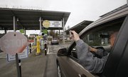 A driver holds up a NEXUS identification card April 9 at a border crossing from Canada into the United States in Blaine, Wash. The NEXUS card, with an embedded radio frequency identification, or RFID, chip that can be read up to 20 feet away, allows pre-screened travelers expedited processing though dedicated traffic lanes between the U.S. and Canada, as well as airports and marine locations.