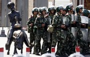 Chinese paramilitary police patrol near a sculpture of a Uighur on a donkey Saturday in Urumqi, China.
