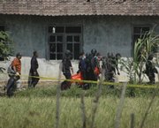 Indonesian riot police carry a body outside of a house following an exchange of gunfire Saturday in Temanggung, Central Java, Indonesia. Indonesian police stormed the house where the regional militant leader suspected in last month’s attacks on hotels in the capital was believed hiding out with several followers, witnesses and police said.