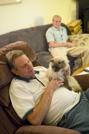 Christopher Paulsen, front, watches “Jeopardy” with roommate Ben Storrud at his Incline Village, Nev., home. Paulsen decided to rent out a room after his son moved out.