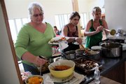 Delaware Street Commons residents, from left, Paula Shaver, Charlotte Pessoni and Heather Putnam, fill their plates at the weekly Sunday potluck.