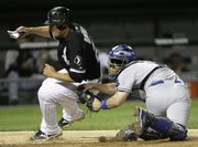 Kansas City catcher John Buck, right, tags out Chicago’s Carlos Quentin at home as he tries to score on a fly out by Alexei Ramirez during the fifth inning. The Royals beat the White Sox, 5-4, Tuesday in Chicago.