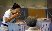 A woman reacts as she casts her vote in Japan’s parliamentary elections today at a polling station in Tokyo.
