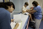 Jack Houley, 10, of Annapolis, Md., prepares to have his blood drawn before receiving a shot of a trial vaccine for the swine flu from Linda Wadsworth, of the University of Maryland, right, as Infectious Disease Specialist Dr. Julia Hutter, left, takes notes during a visit Thursday to Annapolis Pediatrics.