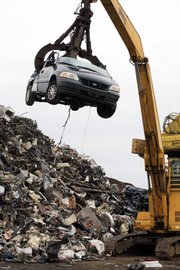 A crane lifts a discarded vehicle to a shredder at Gershow Recycling Corp. in this Aug. 6 file photo in Medford, N.Y. A Fed survey found Wednesday that the majority of regions reported that the government’s Cash for Clunkers program “boosted traffic and sales.” But aside from brisk businesses at auto dealerships, other merchants struggled.