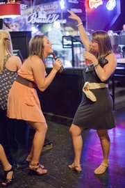 KU students Annie Stopulos, Davenport, Iowa, left, and Alicia Anderson, Prairie Village, sing along to a piano players performance during Ladies’ Night at The Barrel House.