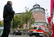 A police officer stands in front of Carolinum school Thursday in Ansbach, Germany. Police say an 18-year-old armed with an ax, knives and homemade bombs attacked his high school in southern Germany, wounding 8 students and one teacher.