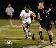 Free State's Diego Gonzalez, left, tries to beat Lawrence High defender Derek Roush to the ball. FSHS beat the Lions, 5-0, Tuesday at FSHS.