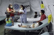 Dr. Toral Shah, standing in the center, talks with Sandy Jiminez, left, before examining her son, Sammi, 4, lying on the cot, during the family’s visit Monday to a tent clinic outside the emergency room at Dell Children’s Hospital in Austin, Texas, where patients with flu symptoms are treated. Other family members are Keren Jiminez, seated on the left; Miguel Jiminez, seated in the background, and their father, Sergio Jiminez, seated on the right. All are from Austin.