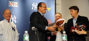 New York Yankees Managing General Partner Hal Steinbrenner, right, receives a football and helmet from Big 12 Commissioner Dan Beebe, left, as Big East Commissioner John Marinatto looks on at a news conference on Wednesday in New York. It was announced that in 2010 a college bowl football game between the Big East and Big 12 will be played at Yankee Stadium.