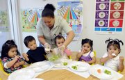 Preschool teacher Jennifer Rosario serves celery to 2-year-olds at the Latin American Community Center in Wilmington, Del. New research from Harvard University shows few states require that child care providers take specific nutrition and physical activity steps to keep the under-5 crowd healthy.