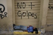 A woman sleeps under graffiti that reads in Spanish, “No more coups” in Tegucigalpa, Honduras, in this Oct. 5 file photo. Hondurans are suffering from a political crisis after the nation’s military ousted President Manuel Zelaya. With aid cut off from the U.S. and E.U., an already fragile economy is under even more duress.