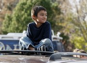 Six-year-old Falcon Heene sits cross-legged Thursday on the roof of his family’s van outside his home in Fort Collins, Colo., after the little boy was found hiding in a box in a space above the garage.