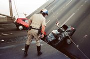 A California Highway Patrol Officer checks the damage to cars that fell when the upper deck of the Bay Bridge collapsed onto the lower deck Oct. 17, 1989, after the Loma Prieta earthquake in San Francisco. Saturday is the 20th anniversary of the Loma Prieta earthquake, which killed 63 people and caused up to $10 billion damage.