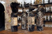 Four bottles of 1875 Armagnac Vieux, covered in a black fungus that looked like matted cat fur and unearthed from a wine cellar this week, are seen Thursday at La Tour d’Argent restaurant in Paris. The restaurant is cleaning out its 450,000-bottle wine cellar — one of the best in the world — and putting 18,000 bottles up for auction in December, an event that has captured the imagination of wine lovers.