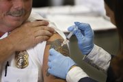 Wayne, Mich., Fire Chief Mel Moore, left, receives the H1N1 vaccine from Kate Guzman on Friday at the Wayne County Department of Public Health. The county administered the vaccine to first responders.