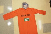 A Halloween costume depicting a space alien in an orange prison jumpsuit labeled “illegal alien” with a “green card” is shown Tuesday in Miami. Immigrant advocates are urging retailers to pull the Halloween costume set, while a group that supports strict immigration laws says such a move impinges on freedom of speech.