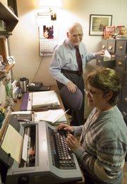 Diane Murry, a medical assistant, uses an electronic typewriter to fill out health insurance forms for Dr. Philip L. Stevens, background, who has used only paper records in his 54 years of practice in Tonganoxie.