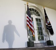 President Barack Obama casts a shadow on the wall as he walks to the podium to speak Friday in the Rose Garden of the White House in Washington.