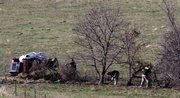 Crime scene investigators dig around a tree line as they look for evidence Wednesday on a rural property in Bates City, Mo. Crews were scouring several acres of a land in connection with the arrest of five men charged with sexually abusing children.