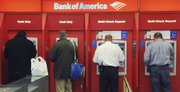 Customers use ATMs at a Bank of America branch office in Boston in this Oct. 16 file photo. The Federal Reserve has issued a new rule that will prohibit banks from charging overdraft fees on ATM and debit card transactions unless a customer allows it. The new rule will take effect July 1.