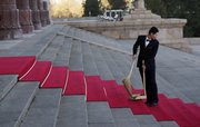 A Chinese staff member looks back as he sweeps a red carpet laid out for U.S. President Barack Obama’s arrival today at the Great Hall of the People in Beijing.