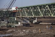 Traffic starts up again across the new I-70 Kansas River bridge after a section of the old bridge, shown on the ground in right side of photo, was dropped by an explosion Thursday.