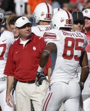 Oklahoma coach Bob Stoops, left, greets quarterback Landry Jones, center, and wide receiver Ryan Broyles (85) as they return to the bench following a touchdown against Texas Tech a week ago in Lubbock, Texas.