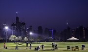 With Jumairah Island towers in the background, people practice golf Friday in Dubai, United Arab Emirates. Investors recoiled from risky assets on Friday and dumped shares in Asian banks and builders, fearing that a Dubai debt default could reignite the financial turmoil of the credit crisis.
