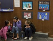 Thirty-five pieces from Sunset Hill School students will become part of the permanent collection of the World Awareness Children’s Museum in Glens Falls, N.Y. The artwork is on display at Meritrust Credit Union, 4821 W. Sixth St., until Dec. 31. From left, Addie Bay and her sister Lily sit with Kahler Wiebe.