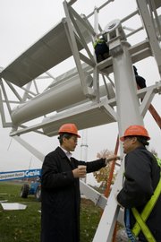 Designer Dr. Seungbae Lee, left, CEO of AeroNet, and his workers prepare to install the AES WindJet 5 Vertical Axis Twin-Rotor Wind Turbine behind A.L. Huber, a construction company, last month in Overland Park.