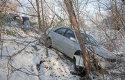 Kevin Raasch, owner of TransMasters Towing, climbs up a steep incline after attaching chains to a Toyota Camry near Inverness and Heritage. Slick streets Wednesday morning contributed to the vehicles slide off Inverness and into the steep ravine. No injuries were reported in connection with the accident.