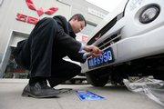 A car dealer attaches the new number plate to a recently sold small van at a GM joint venture dealership in Chengdu, in southwestern China’s Sichuan province Nov. 26. China has overtaken the U.S. as the world’s biggest market for automobiles, the first time any other country has bought more vehicles than the nation that produced Henry Ford, the Cadillac and the minivan.