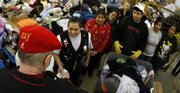 Wearing an “Elf” hat, the Kansas City Secret Santa distributes $100 bills to people at a Kansas City, Kan., thrift store Wednesday. He is recruiting young teens to go with him on his rounds of the Kansas City area.